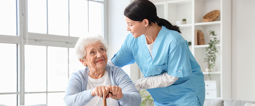 Nurse leaning down and speaking with an elderly resident.